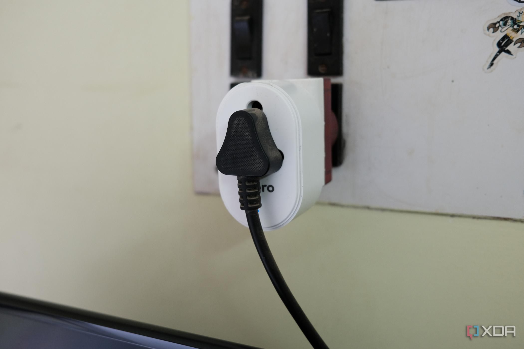 Photo of a TV plug inserted into a smart plug which is put on a wall outlet for smart home automation