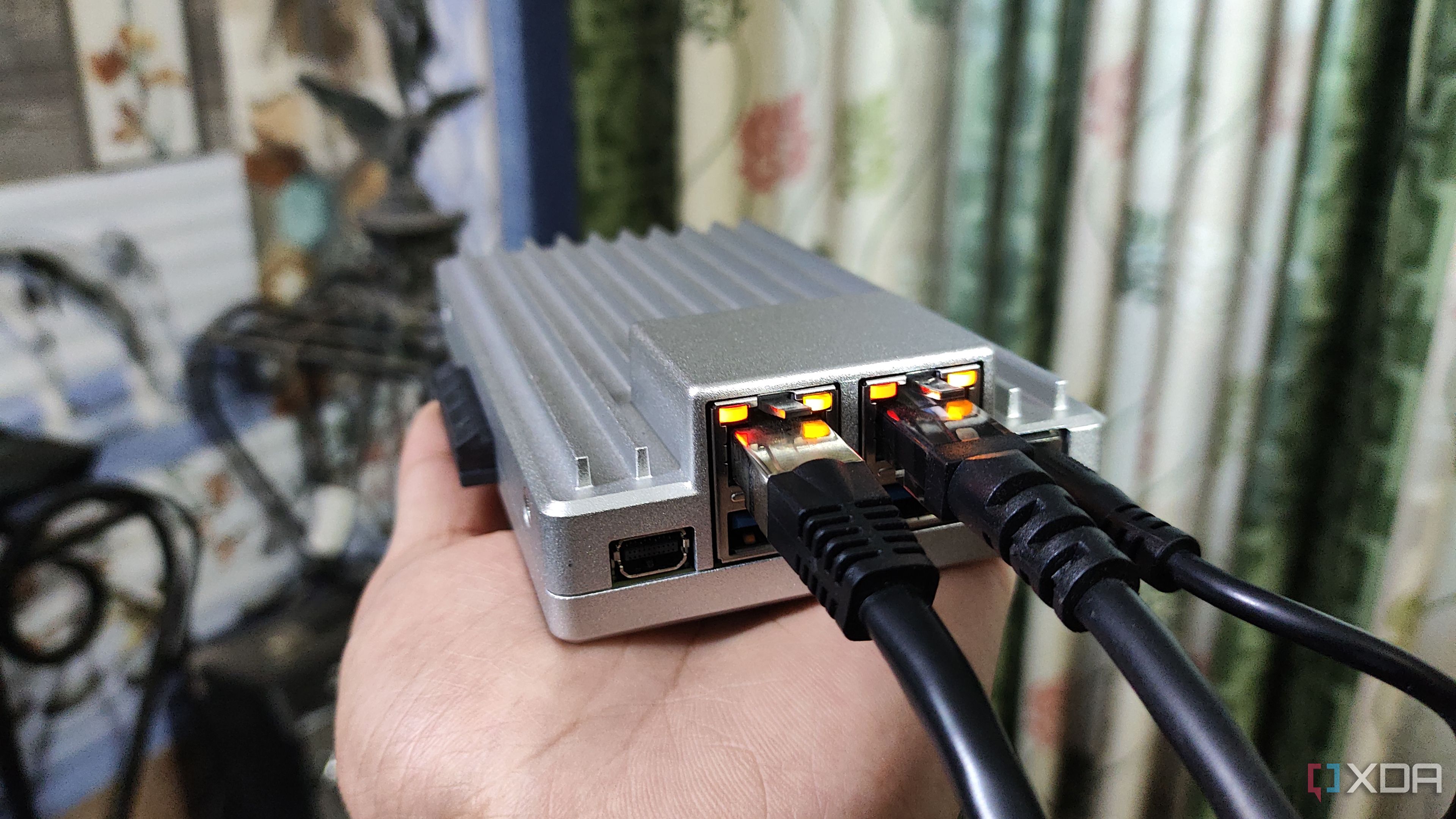 A person holding a ZimaBoard 2, with two Ethernet cables plugged into the SBC