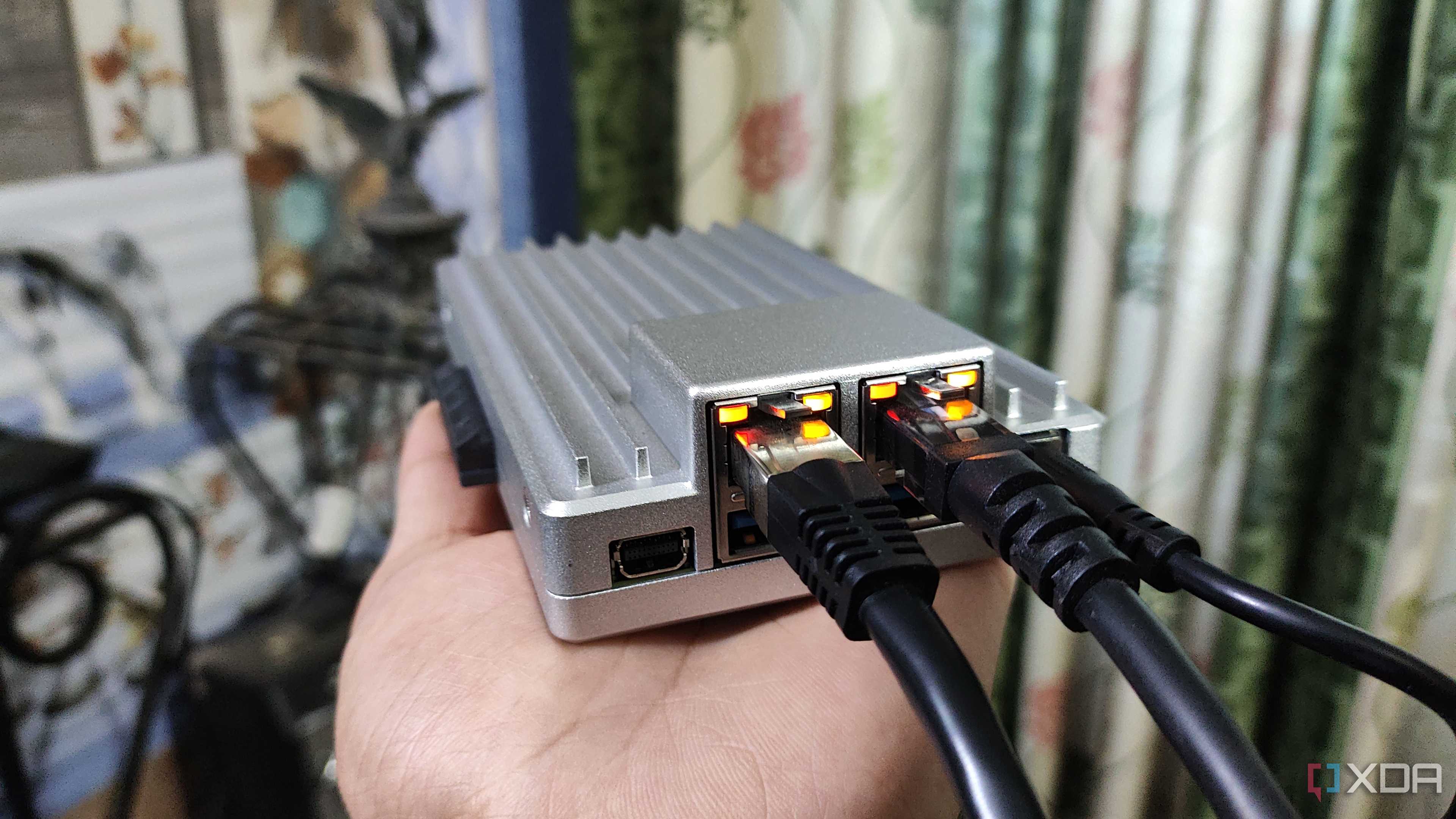 A person holding a ZimaBoard 2, with two Ethernet cables plugged into the SBC