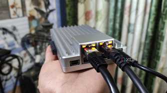 A person holding a ZimaBoard 2, with two Ethernet cables plugged into the SBC