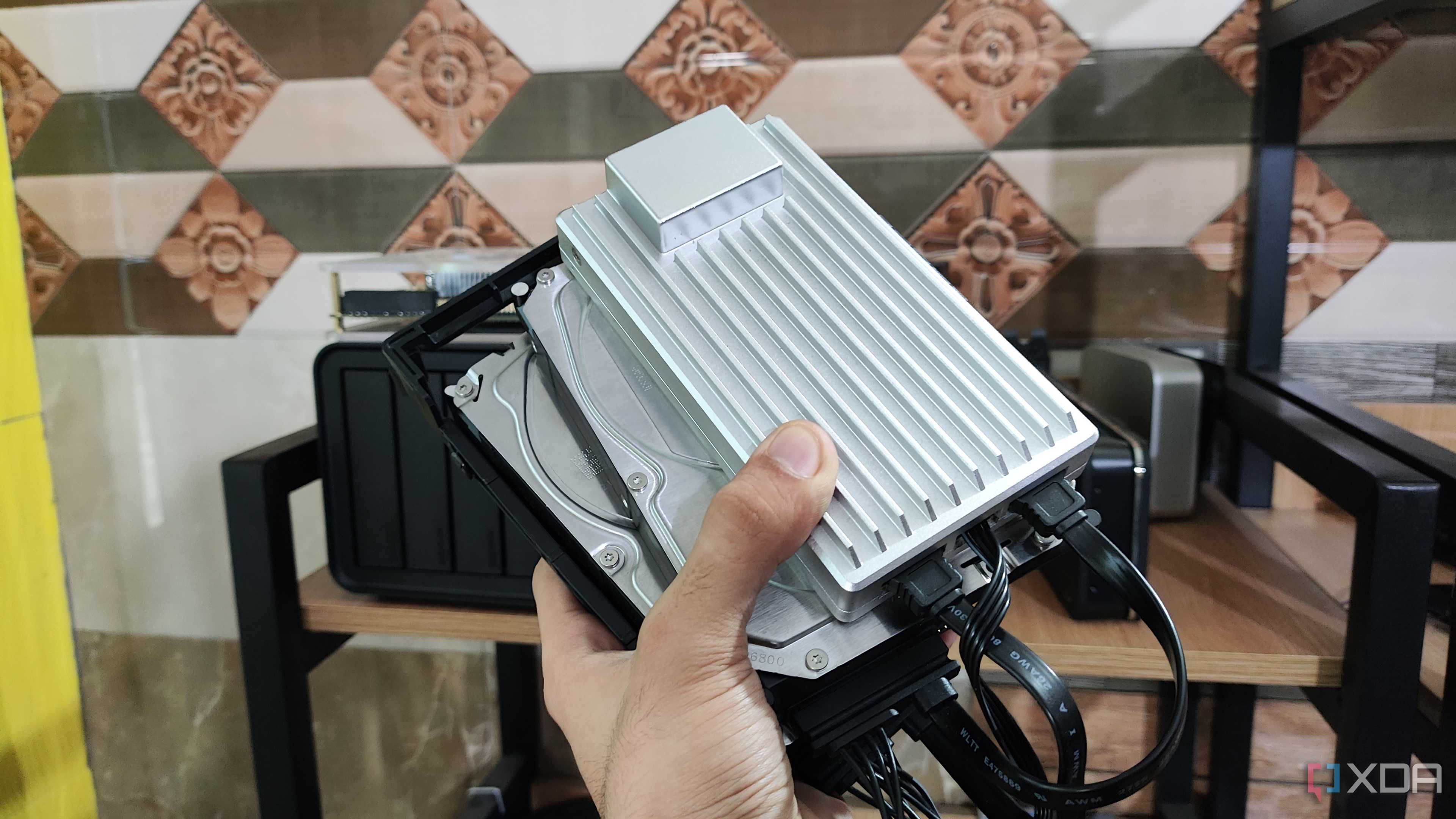 A person holding a ZimaBoard 2 alongside two drives