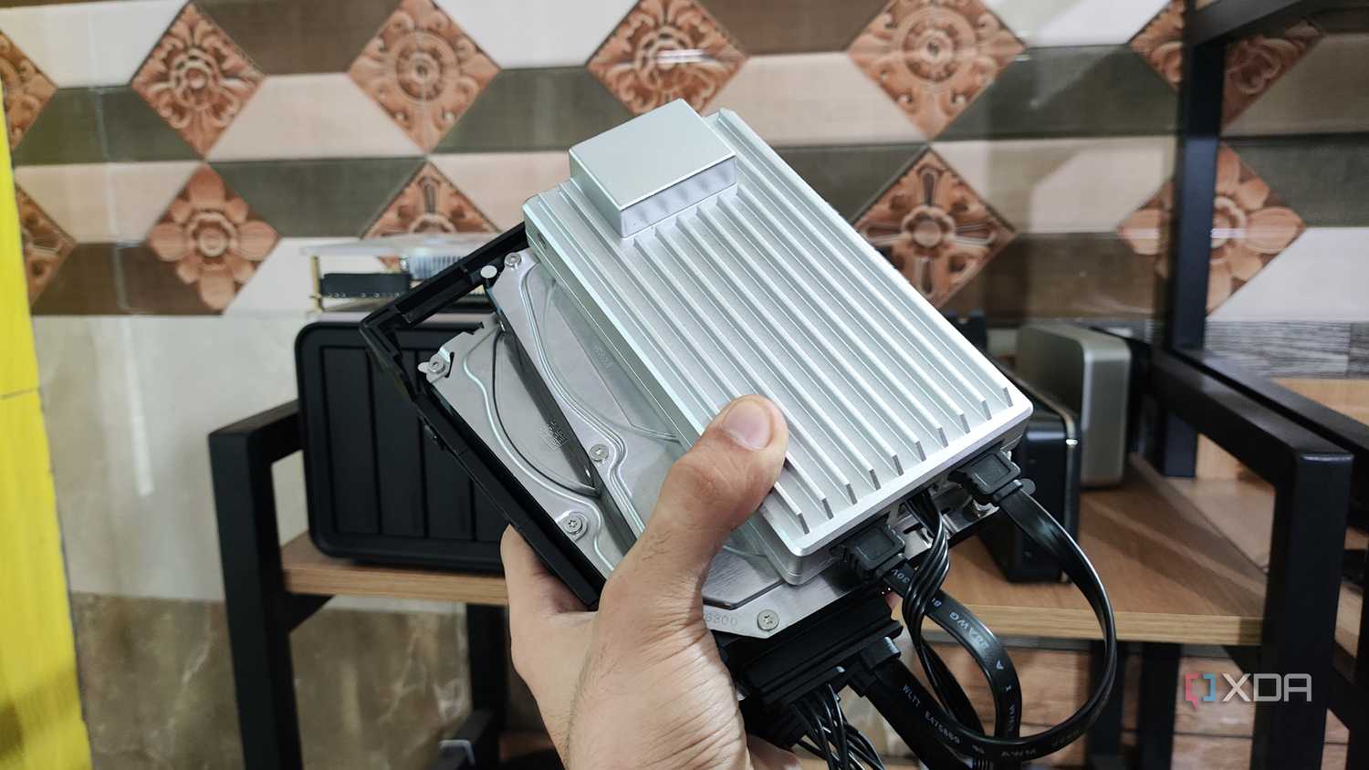 A person holding a ZimaBoard 2 alongside two drives
