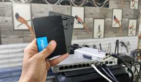 A person holding two SSDs, with a ZimaBoard 2 lying in the background