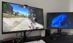 A photo of a gaming setup displaying an FPS game with two monitors