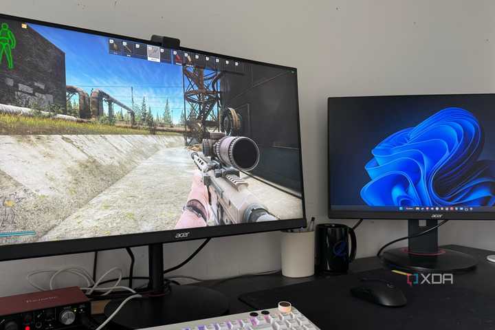 A photo of a gaming setup displaying an FPS game with two monitors