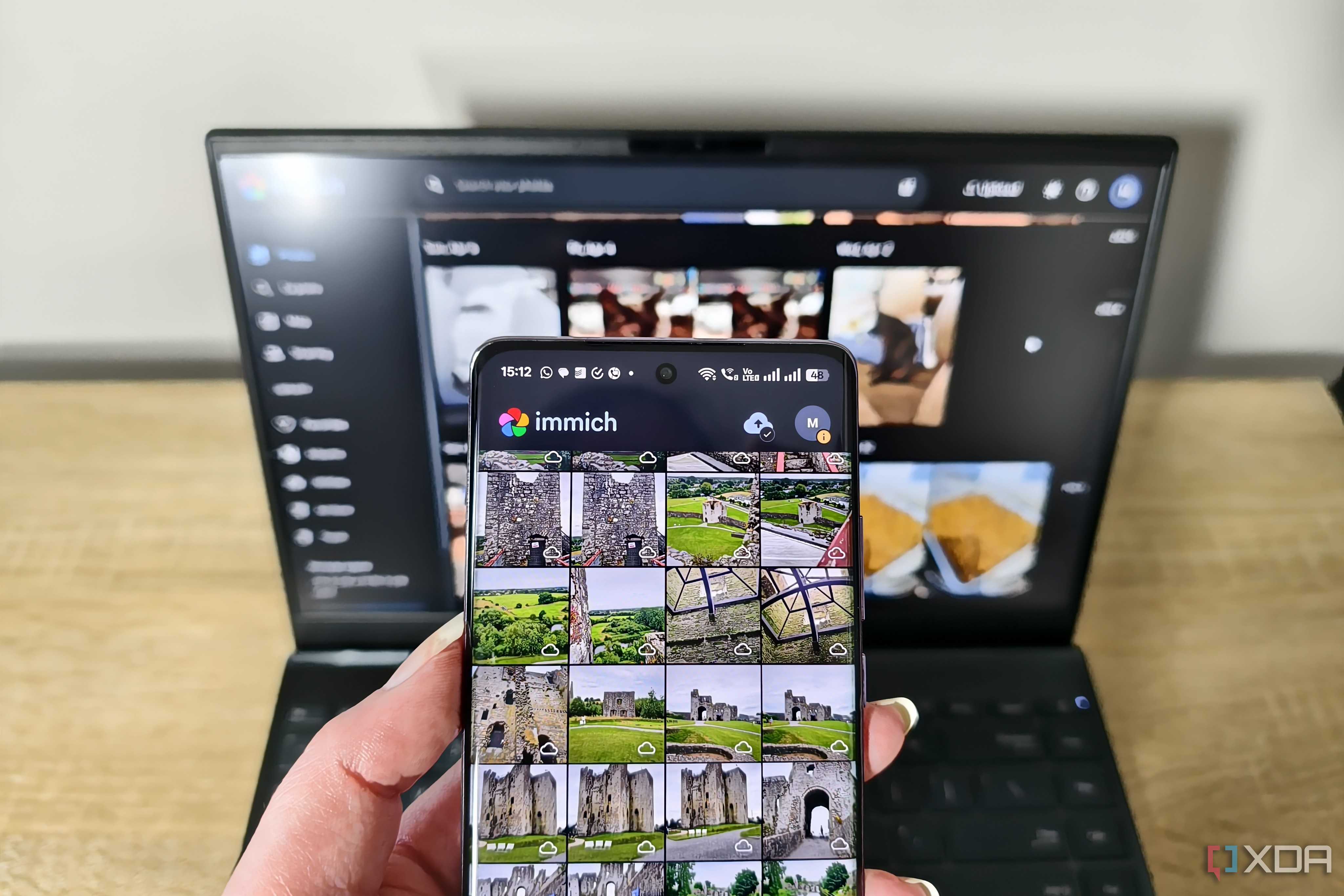immich app on a smartphone with laptop in background
