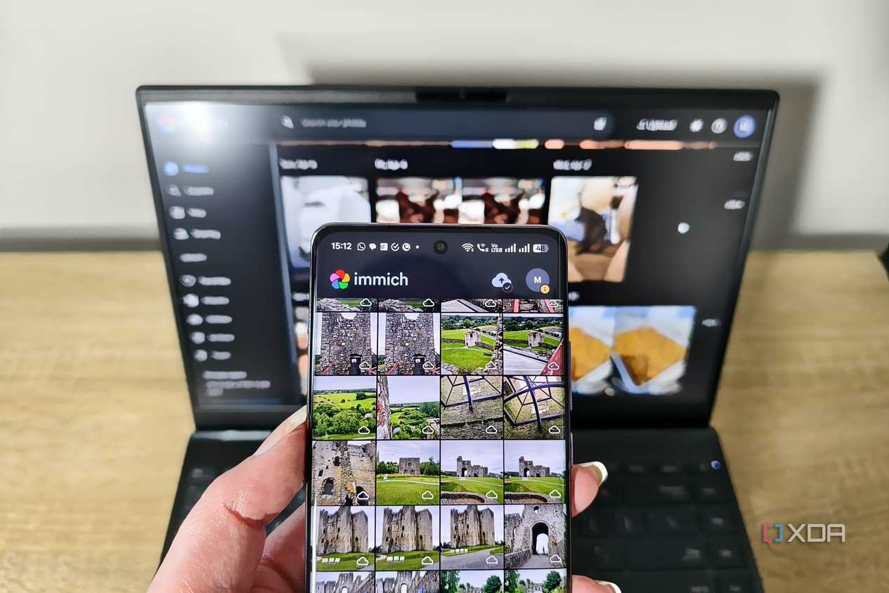 immich app on a smartphone with laptop in background