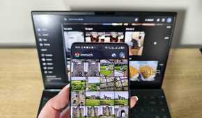immich app on a smartphone with laptop in background