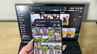 immich app on a smartphone with laptop in background