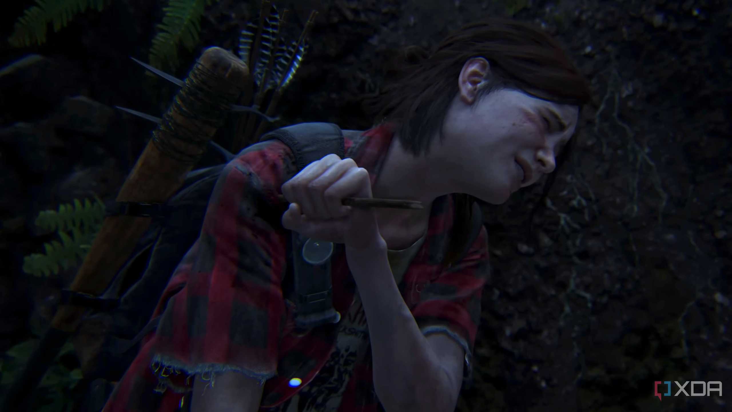 Ellie wincing in pain while removing an arrow from her shoulder in The Last of Us Part II.