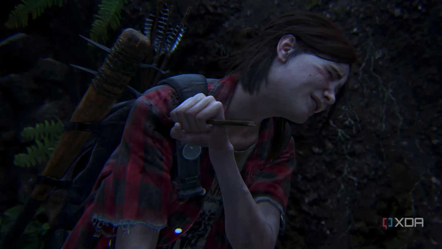 Ellie wincing in pain while removing an arrow from her shoulder in The Last of Us Part II.