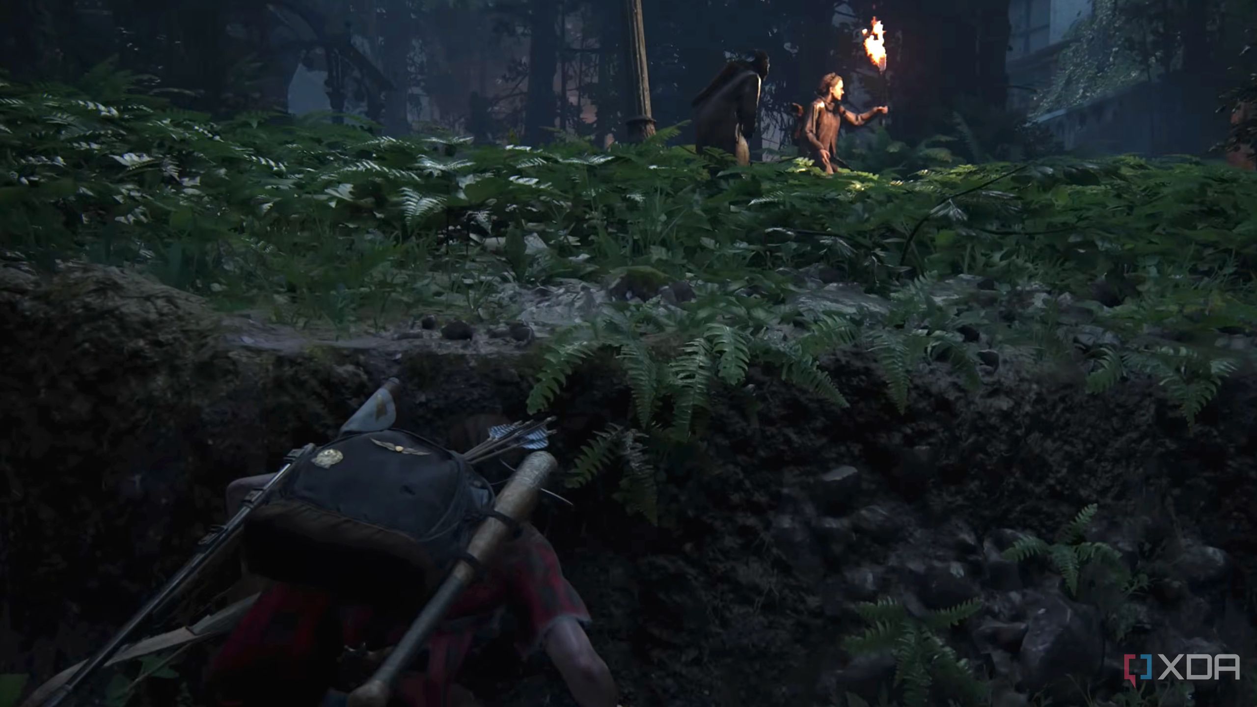 Ellie hiding from Seraphites with flaming torches in The Last of Us Part II. 