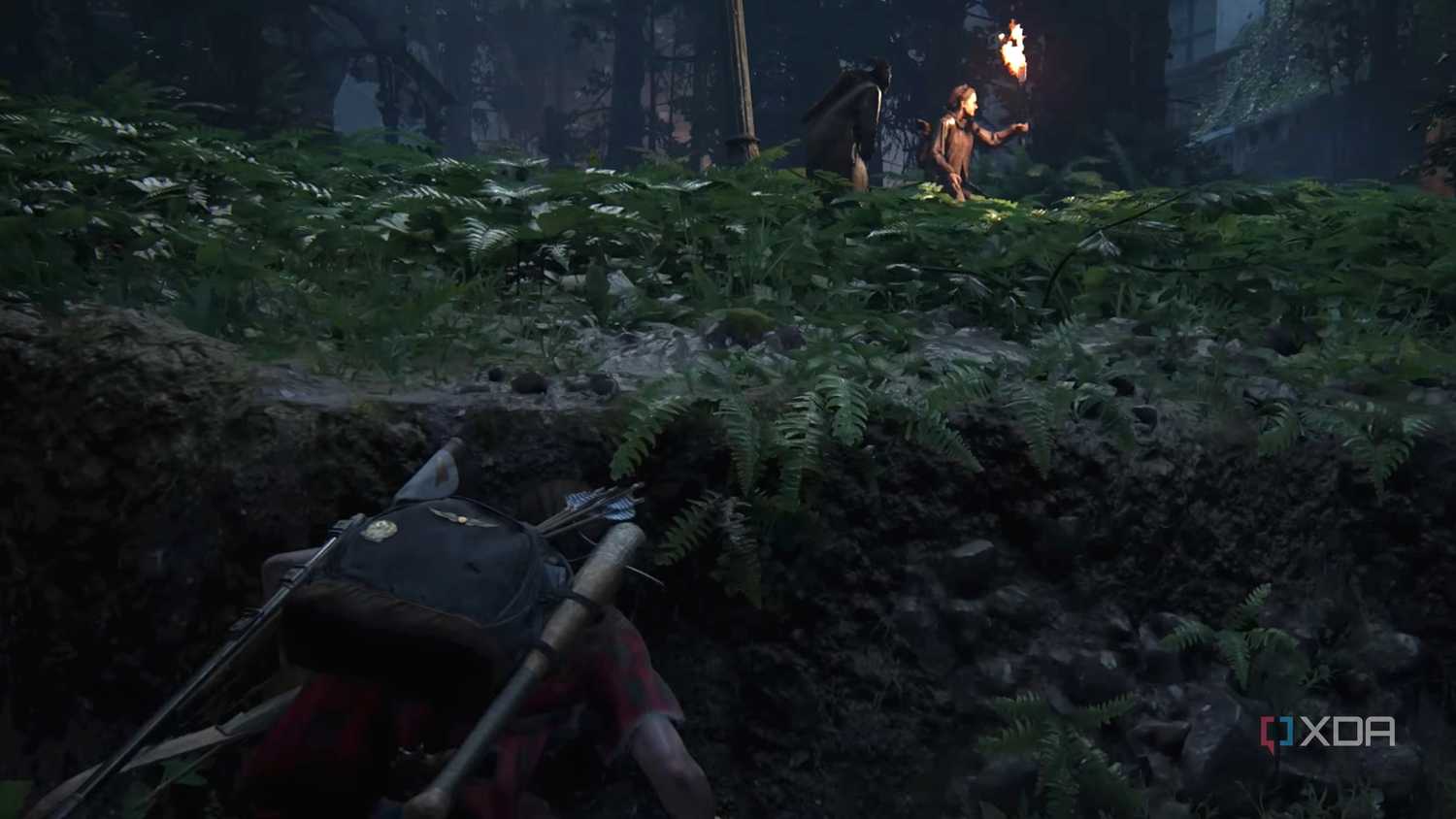 Ellie hiding from Seraphites with flaming torches in The Last of Us Part II.