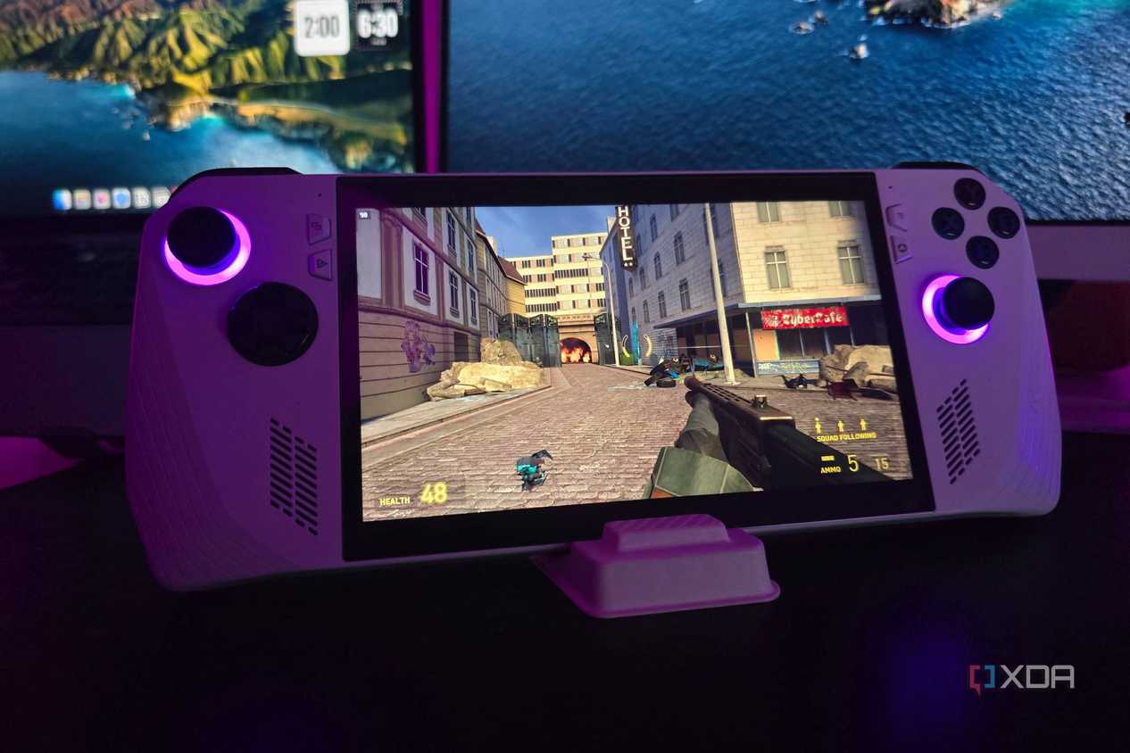 Asus ROG Ally running Half-Life 2 with a MacBook and a monitor in the background