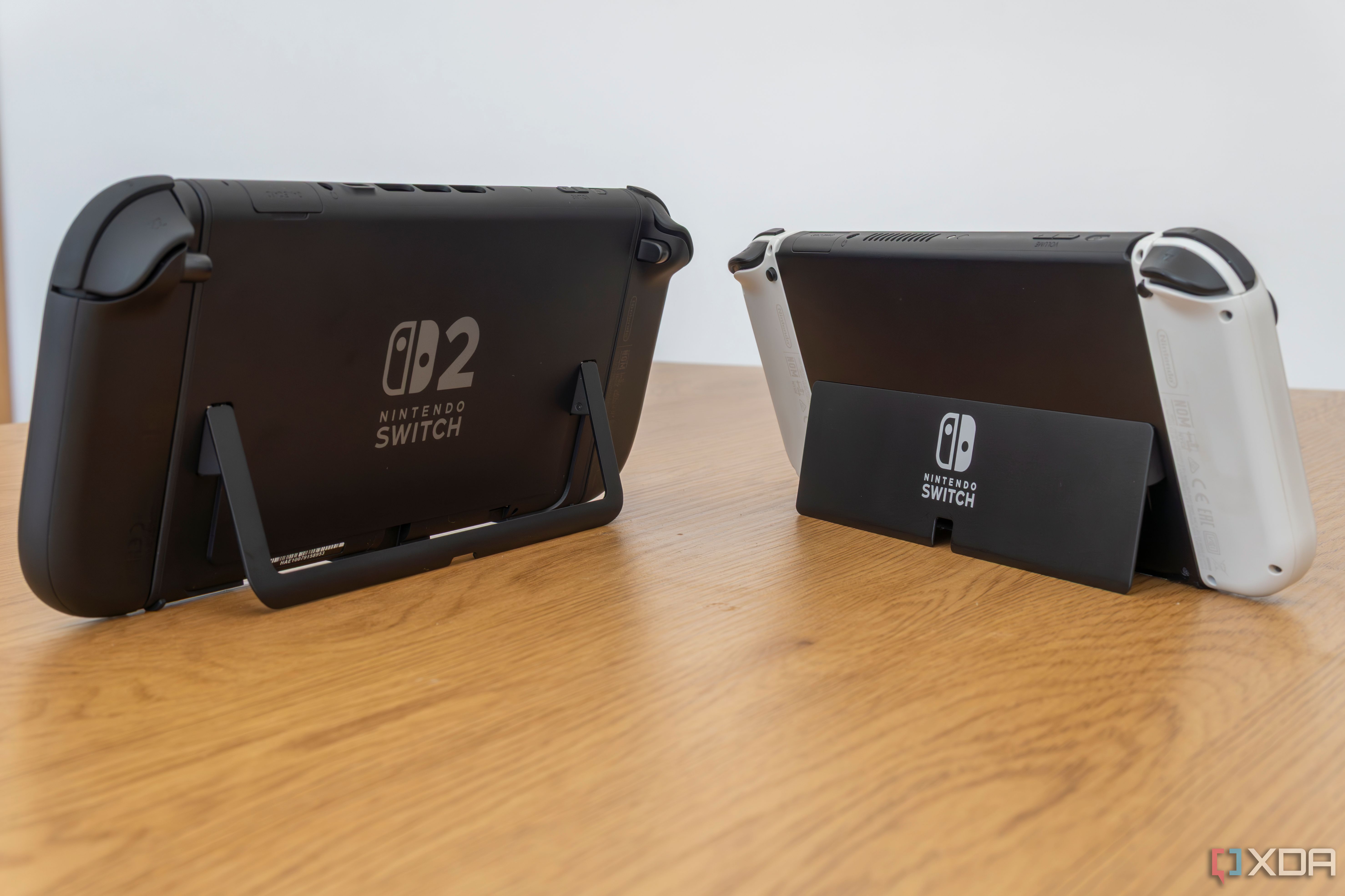 Angled rear view of a Nintendo Switch 2 and a Nintendo Switch OLED model showing both kickstand in use