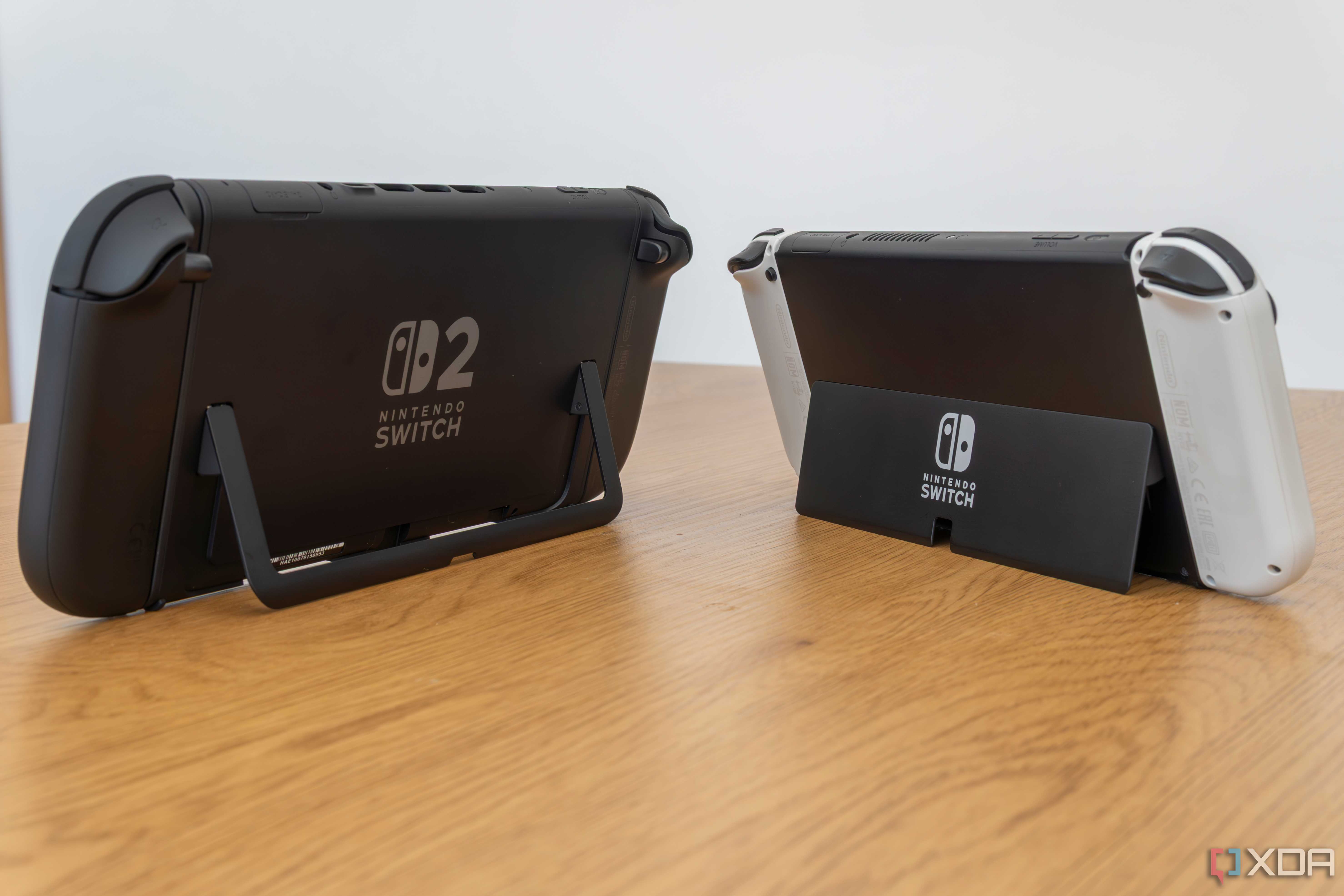 Angled rear view of a Nintendo Switch 2 and a Nintendo Switch OLED model showing both kickstand in use