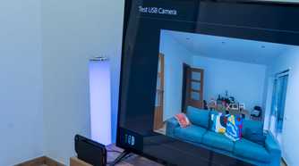 A Nintendo Switch 2 in the dock with a Trust USB webcam connected and showing a preview of the video feed on the TV
