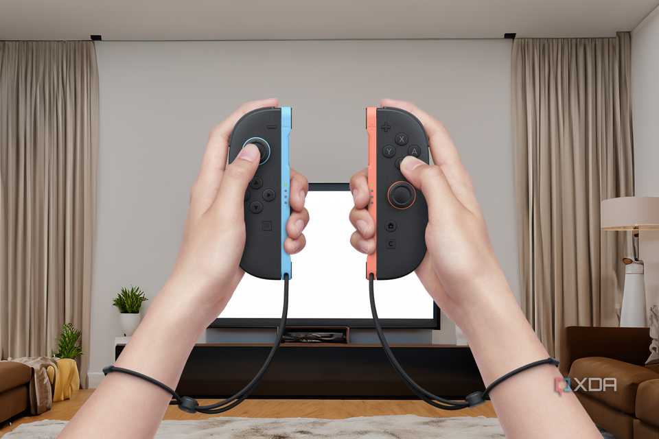 Two hands holding a pair of Joy-Con 2 controllers in front of a TV in a living room