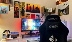 A gaming PC and gaming chair with video game art paintings on the wall.