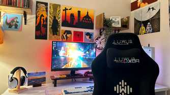 A gaming PC and gaming chair with video game art paintings on the wall.