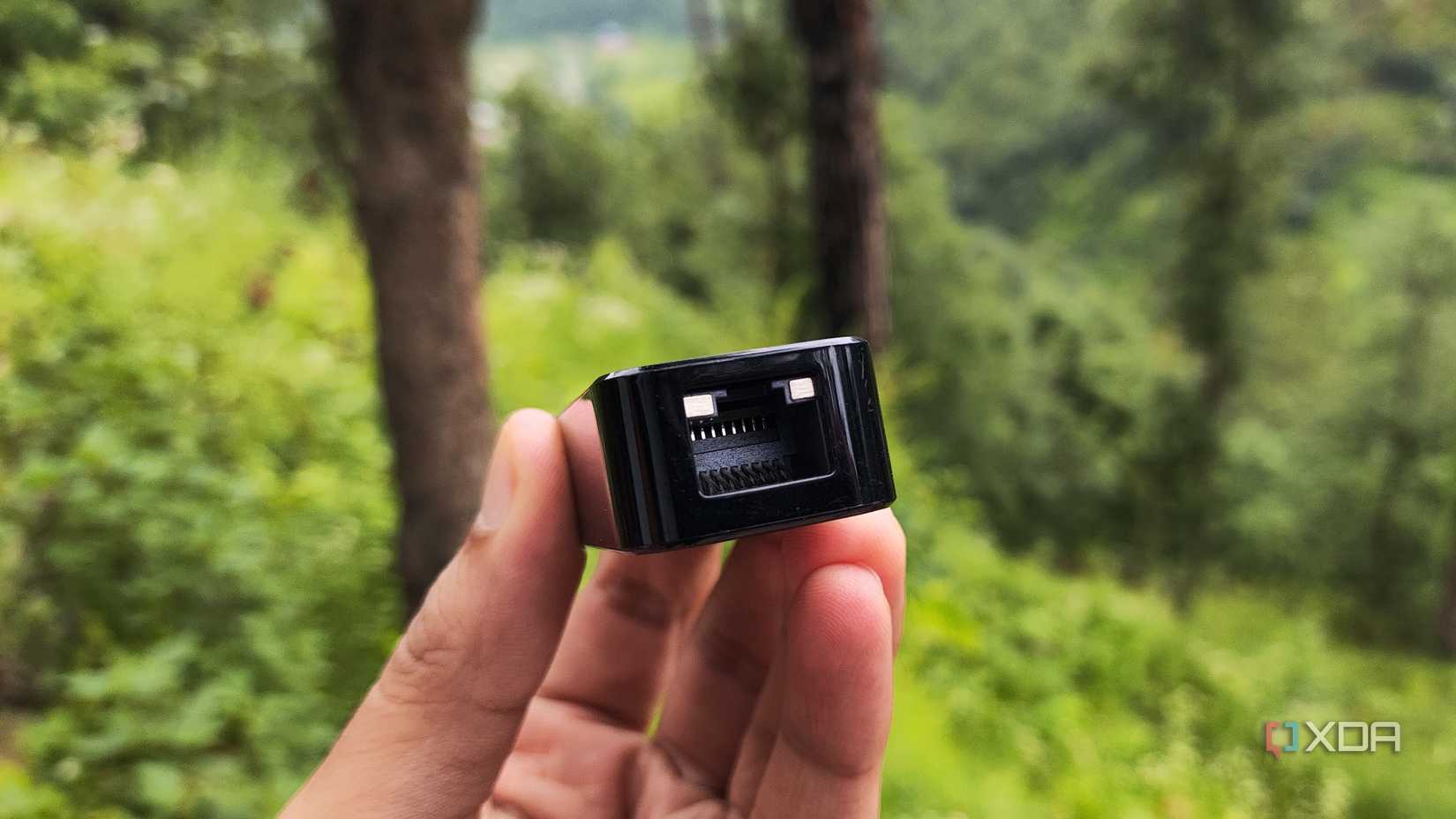 A person holding a USB to Ethernet adapter