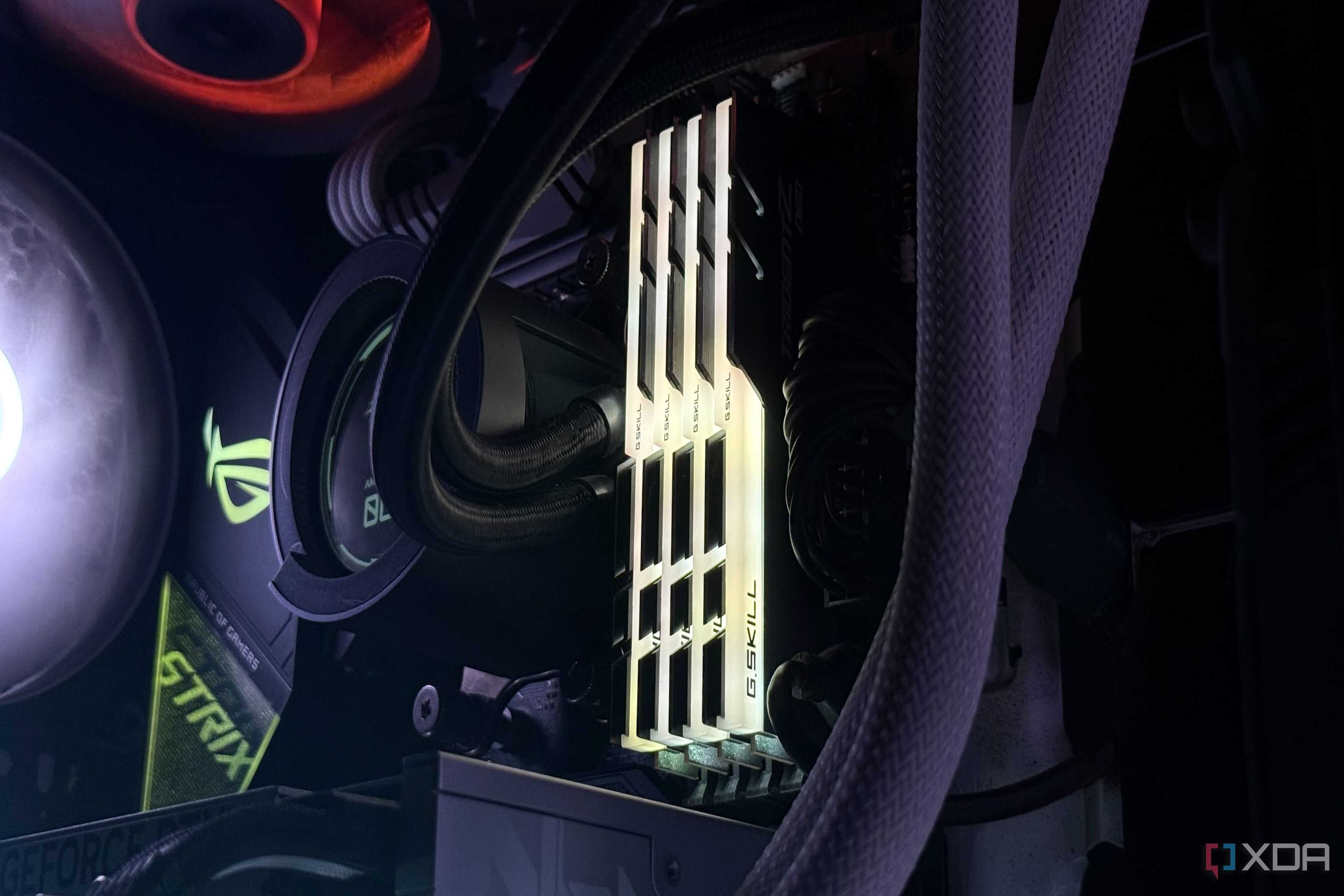 An image of an RGB DDR4 RAM kit installed on a motherboard illuminated in a yellow glow.