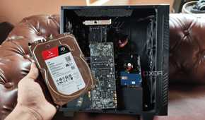 A person holding an HDD in front of a custom-built NAS