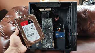 A person holding an HDD in front of a custom-built NAS
