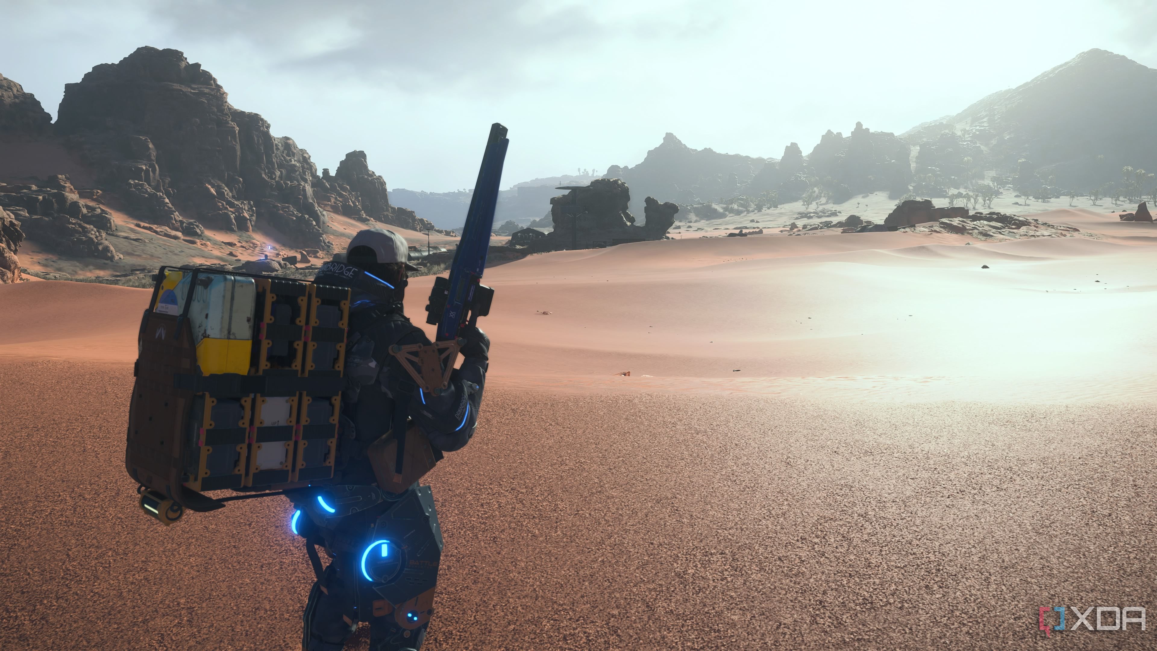Sam holding a sniper rifle in the desert in Death Stranding 2.