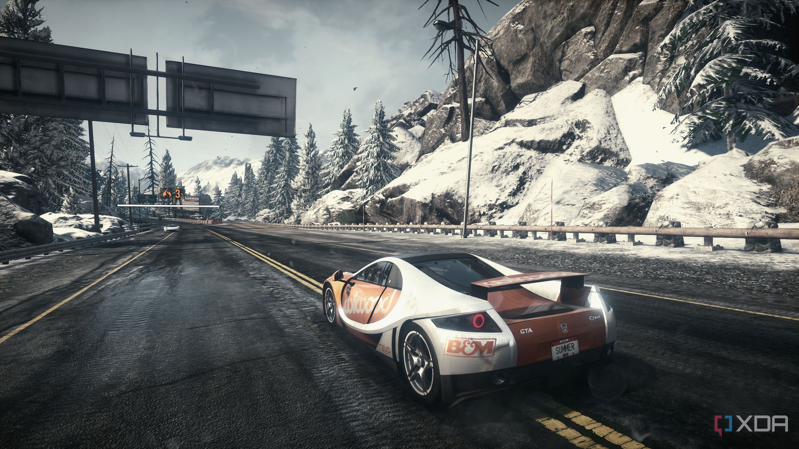 Rear side shot of a GTA Spano driving through snowy mountains.