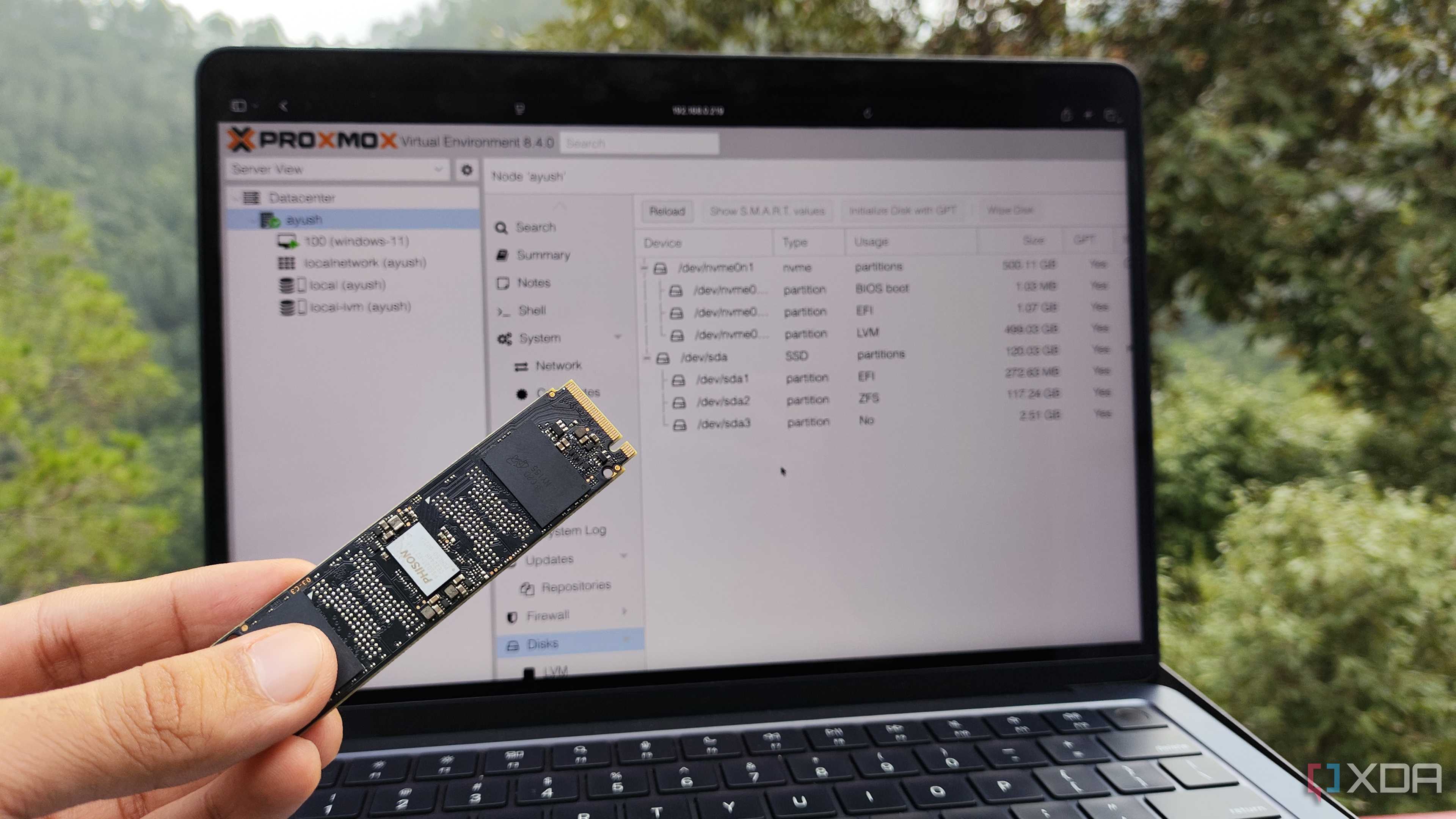 A person holding an SSD in front of Proxmox's web UI