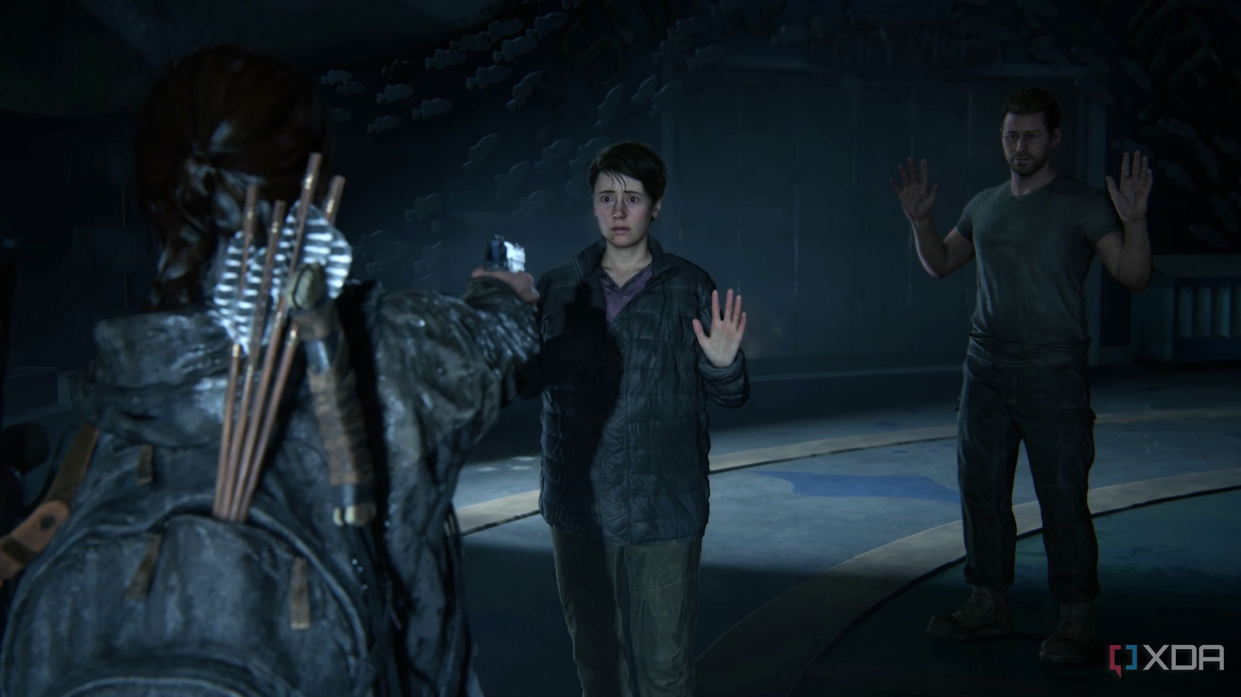 Ellie holding Owen and Mel at gunpoint in The Last of Us Part II Remastered.