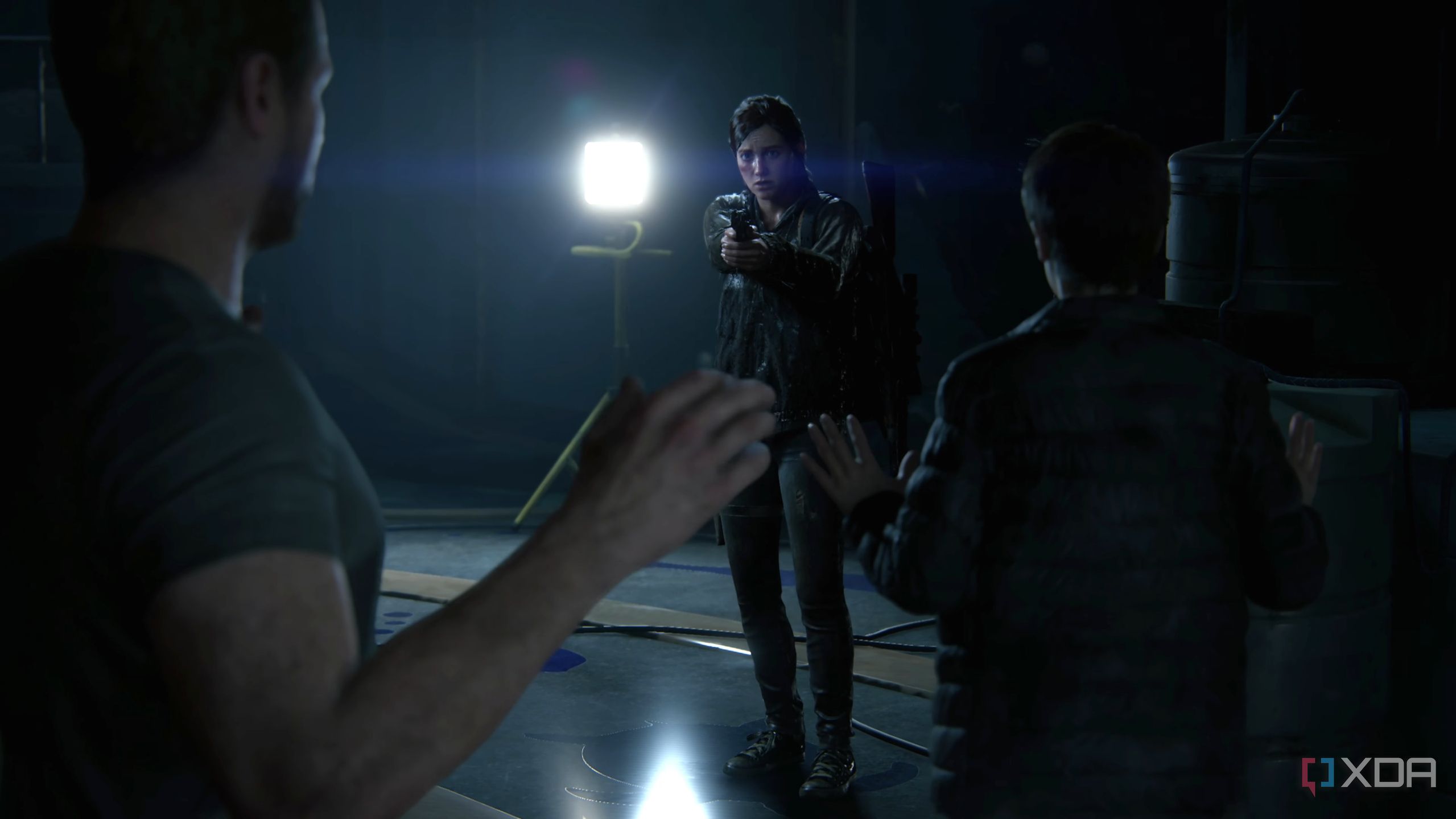 Ellie holding Owen and Mel at gunpoint in The Last of Us Part II Remastered.
