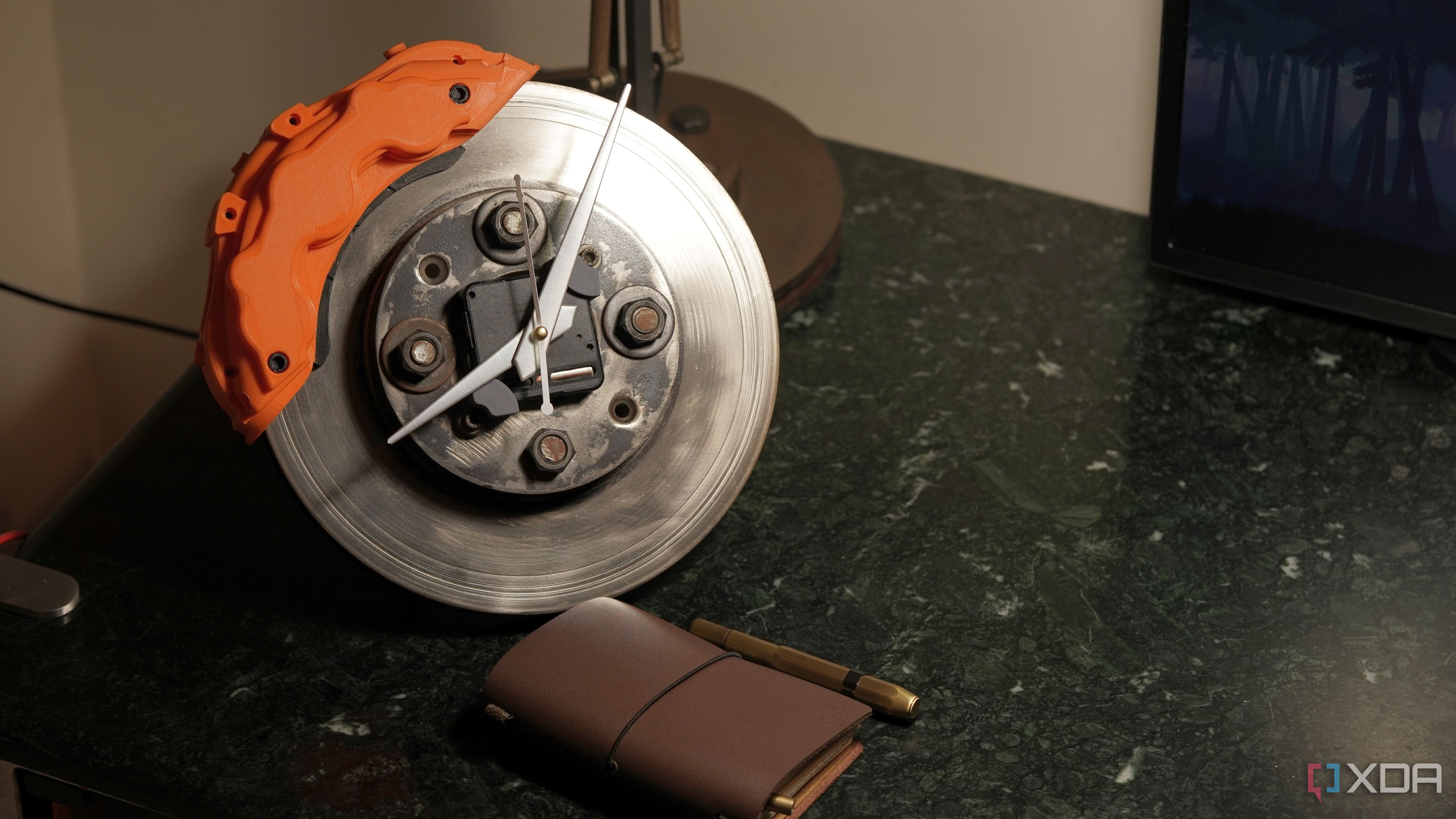 A brake rotor clock with a pocket notebook on a marble table 