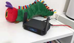 glinet gl-be3600 travel router on a bookshelf