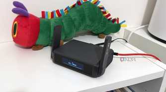 glinet gl-be3600 travel router on a bookshelf