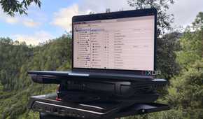 Multiple old laptops, with a MacBook displaying the Proxmox UI resting on top of them