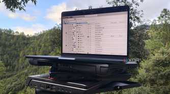 Multiple old laptops, with a MacBook displaying the Proxmox UI resting on top of them