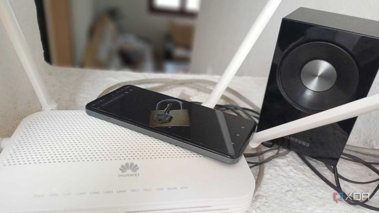 A router with a phone displaying a lock beside a Samsung speaker