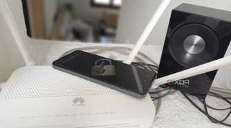 A router with a phone displaying a lock beside a Samsung speaker