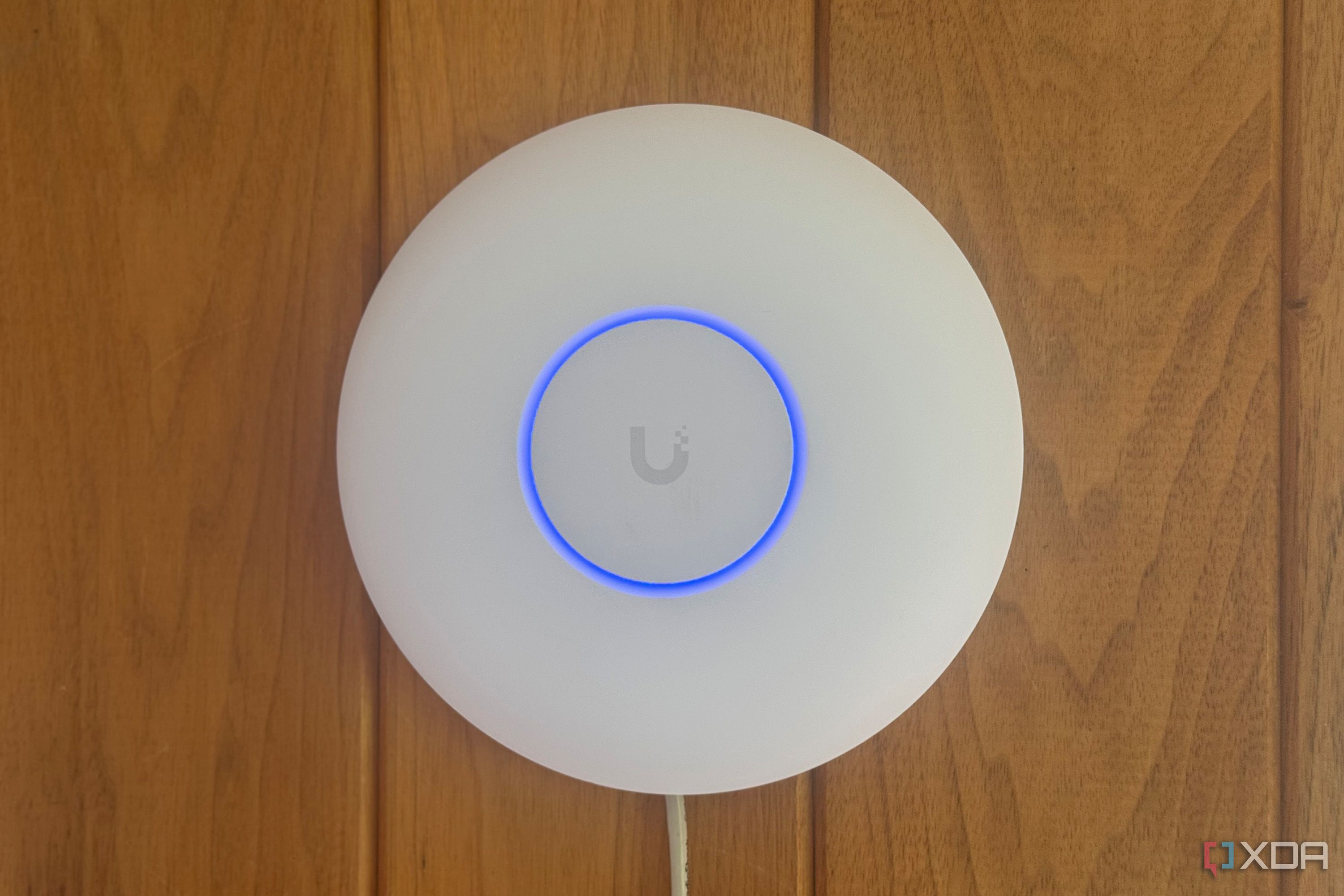 Ubiquiti access point mounted to a wood panel wall in an old college dorm