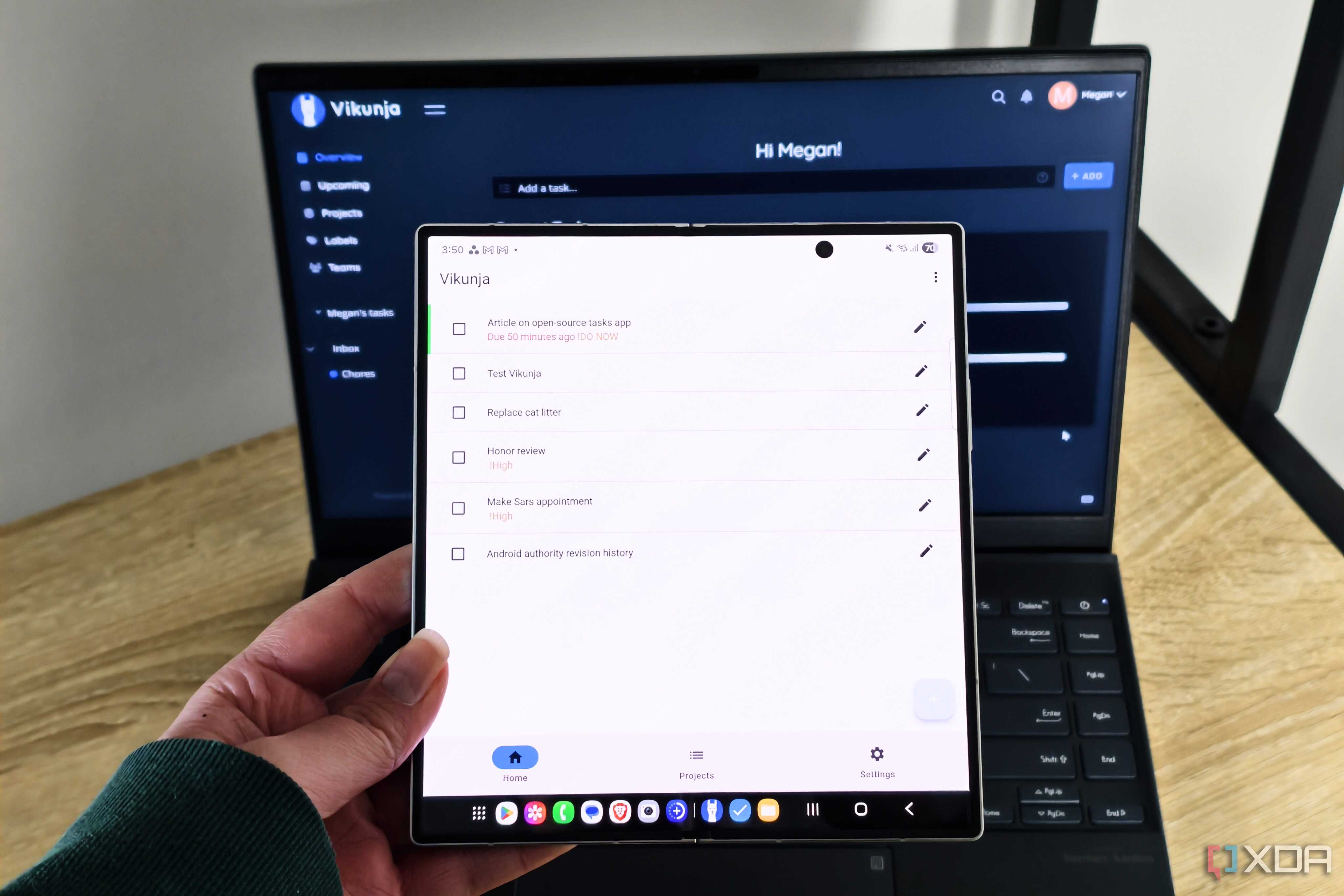 vikunja app on a foldable phone with a laptop in the background