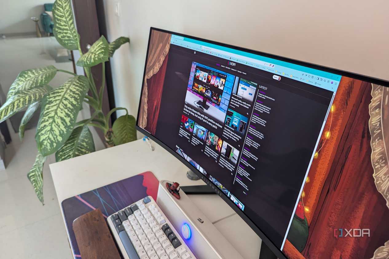 A curved ultrawide monitor on a desk next to a plant