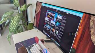 A curved ultrawide monitor on a desk next to a plant