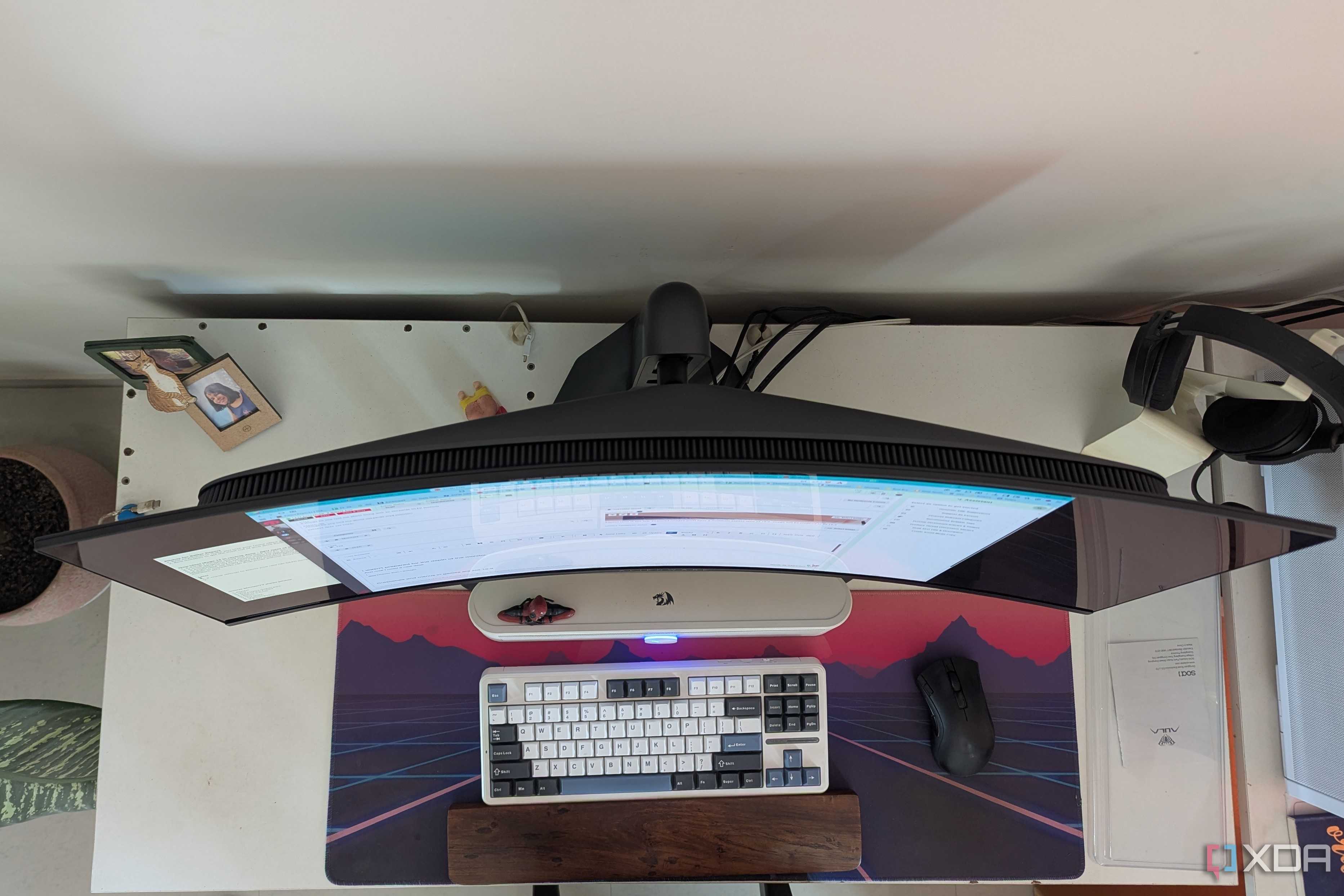 Top view of a curved monitor on a desk next to a keyboard and mouse