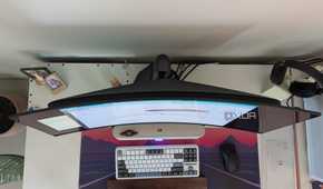 Top view of a curved monitor on a desk next to a keyboard and mouse