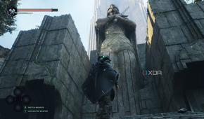 Remi standing next to a gigantic statue in Hell is Us.