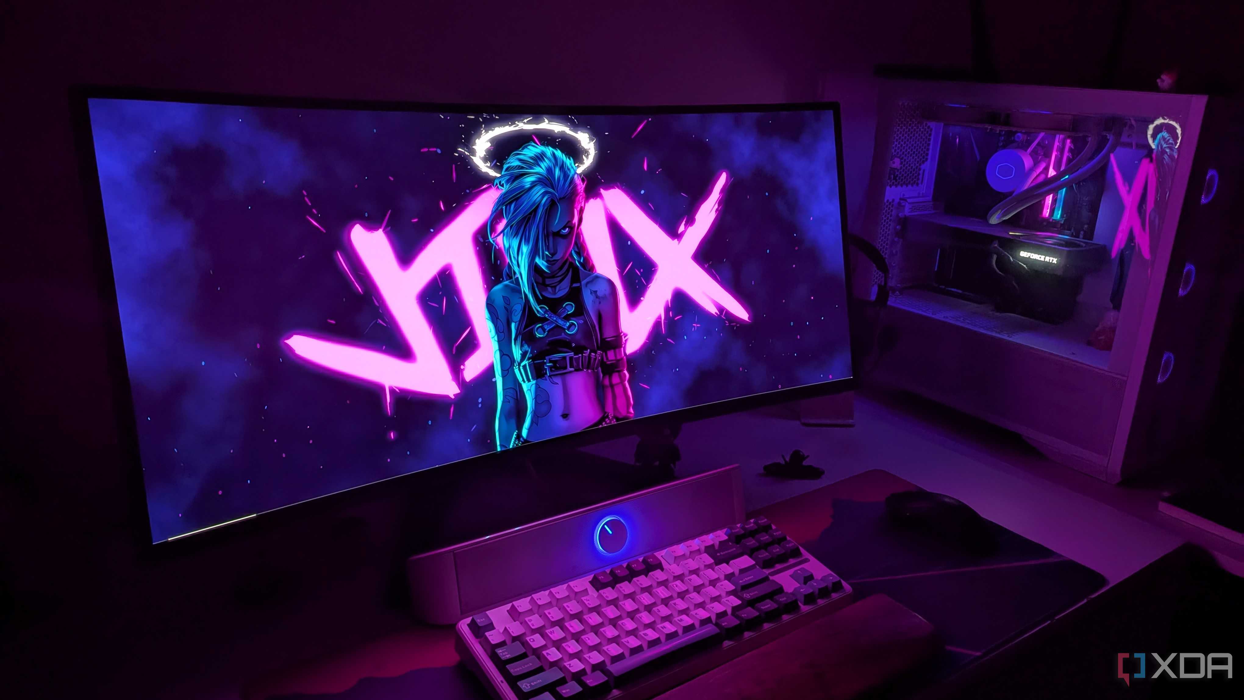 A curved OLED monitor next to a gaming PC on a desk