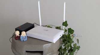 A white router on a stand next to green leaves