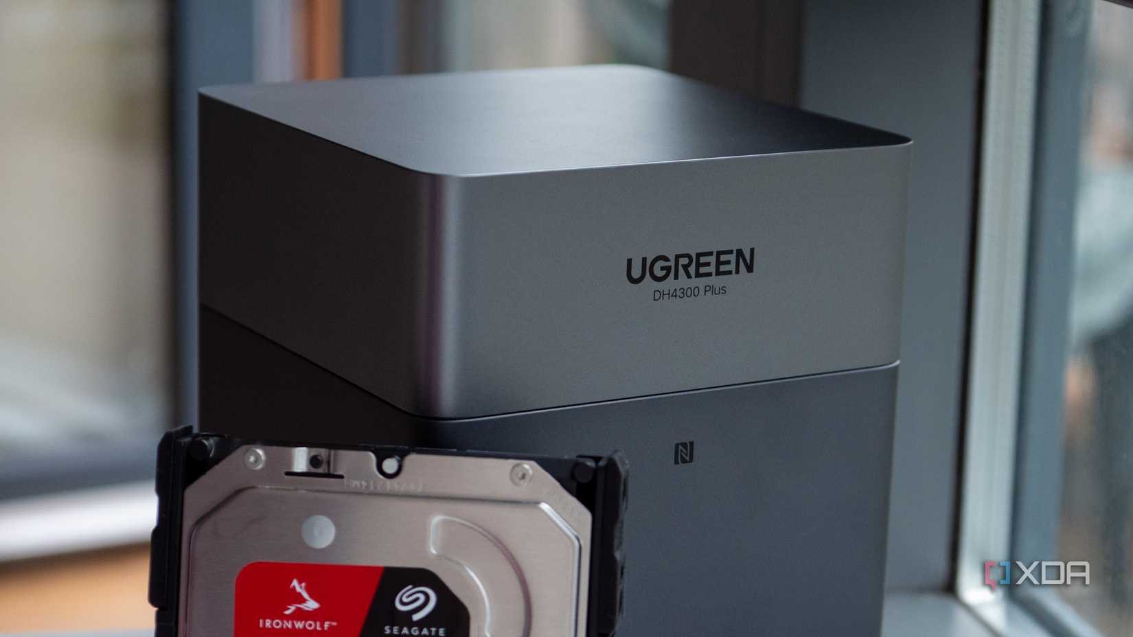 Caja gris UGREEN DH4300 Plus con un disco duro Seagate IronWolf parcialmente insertado. El texto en el dispositivo dice "UGREEN DH4300 Plus."